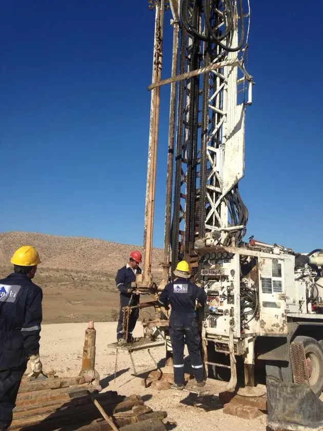 Workers working on a drilling rig in a desert environment.