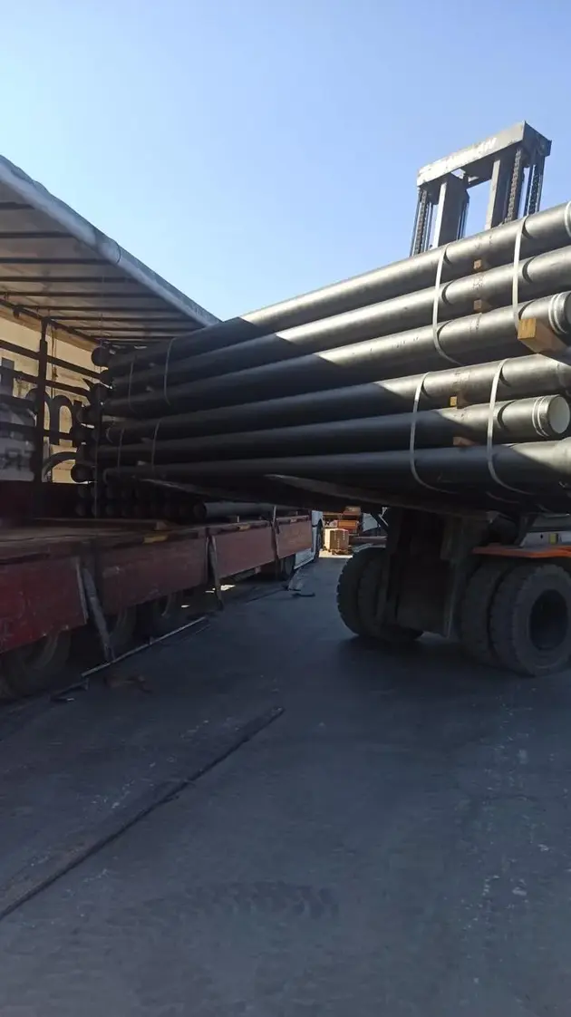 A forklift loading ductile iron pipes onto a truck for transportation.