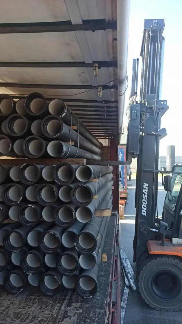 Ductile iron pipes being loaded onto a truck with a forklift inside a container.